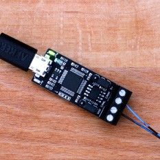 An image of a black circuit board with a USB cable and twisted wire pair on opposite sides.